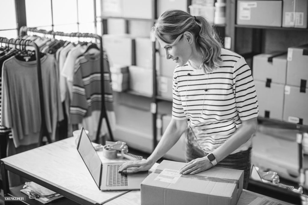 Mature woman at online shop. She is owner of small online shop. Receiving orders and packing boxes for delivery.